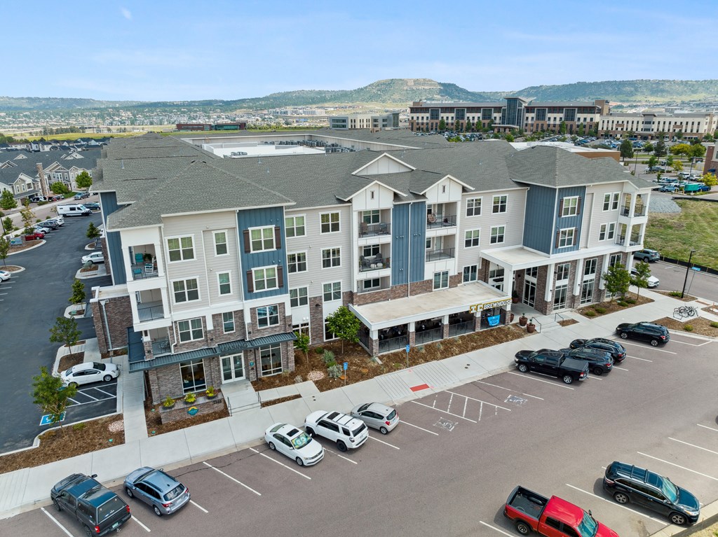an aerial view of an apartment complex with a parking lot and mountains in the background