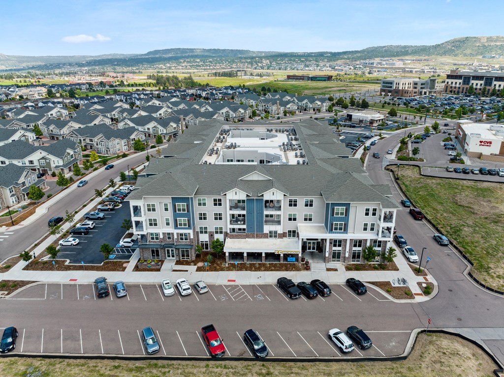 an aerial view of a large apartment complex with a parking lot and mountains in the background