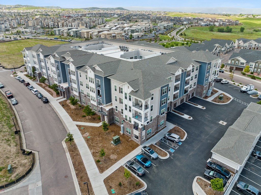 an aerial view of a large apartment complex with a parking lot and grassy field in the