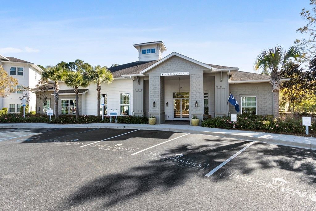 the front of a building with a parking lot and palm trees