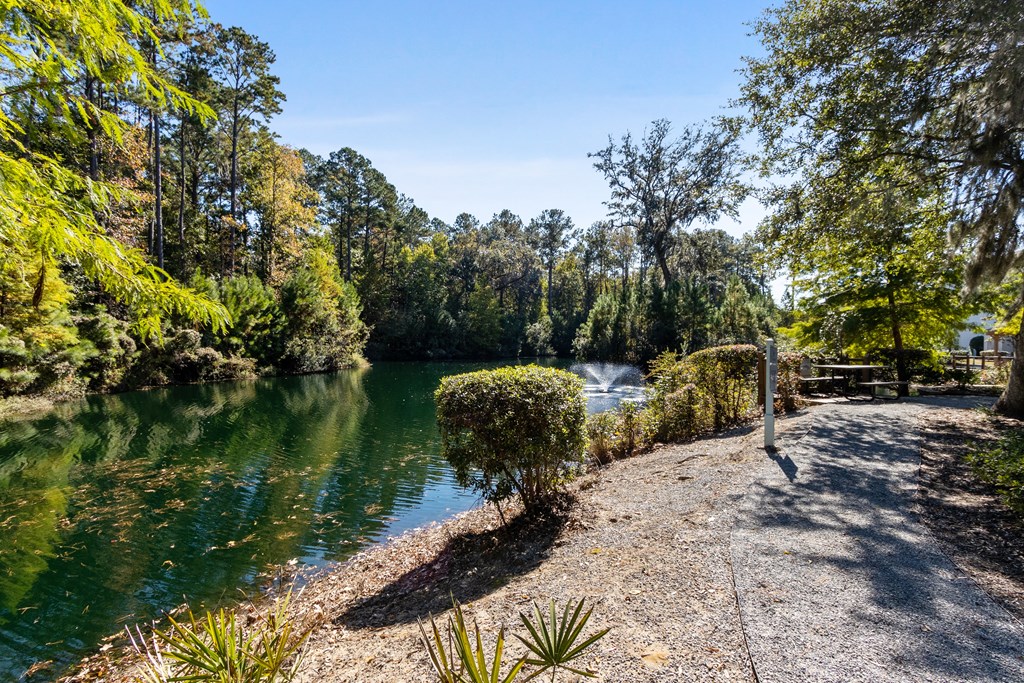 a path next to a river with a fountain