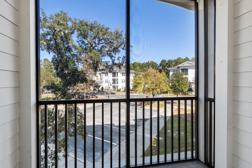 the view from a balcony of a building overlooking a parking lot and trees