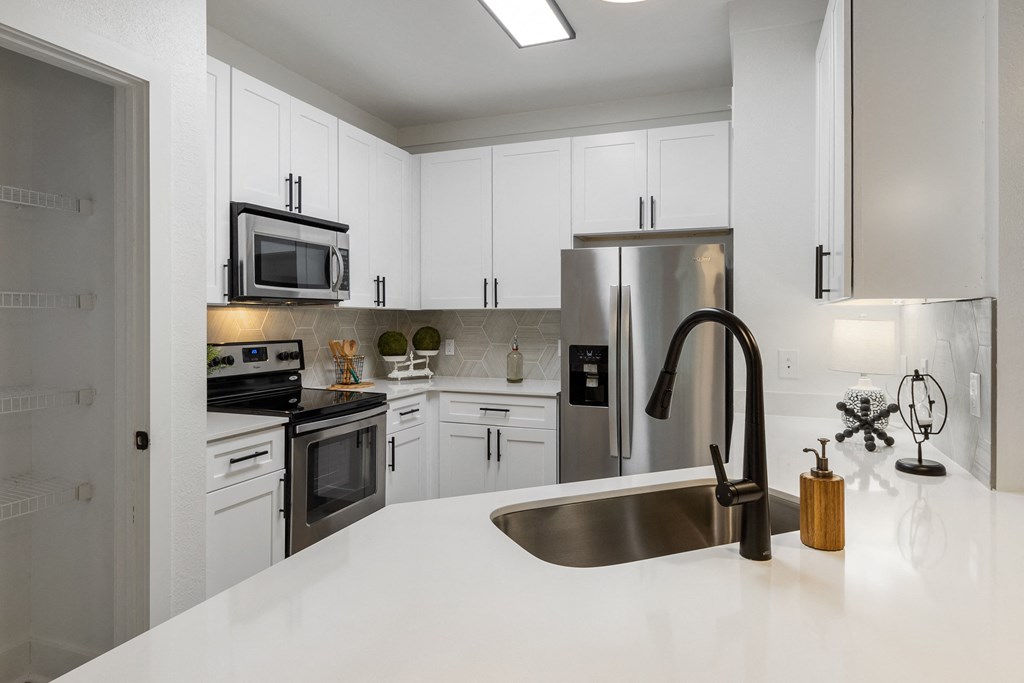 a kitchen with white cabinets and stainless steel appliances and a sink