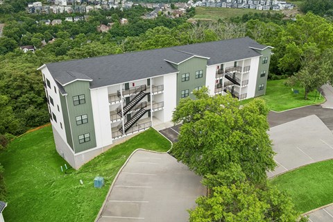 A large green and white building with a parking lot in front.