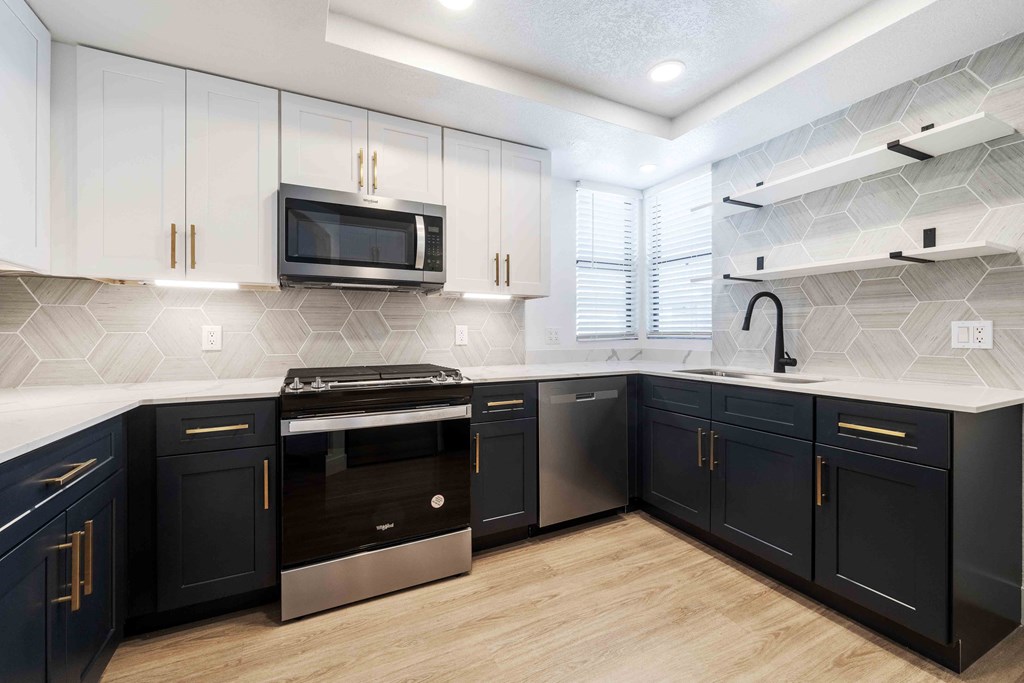 a kitchen with blue and white cabinets and stainless steel appliances
