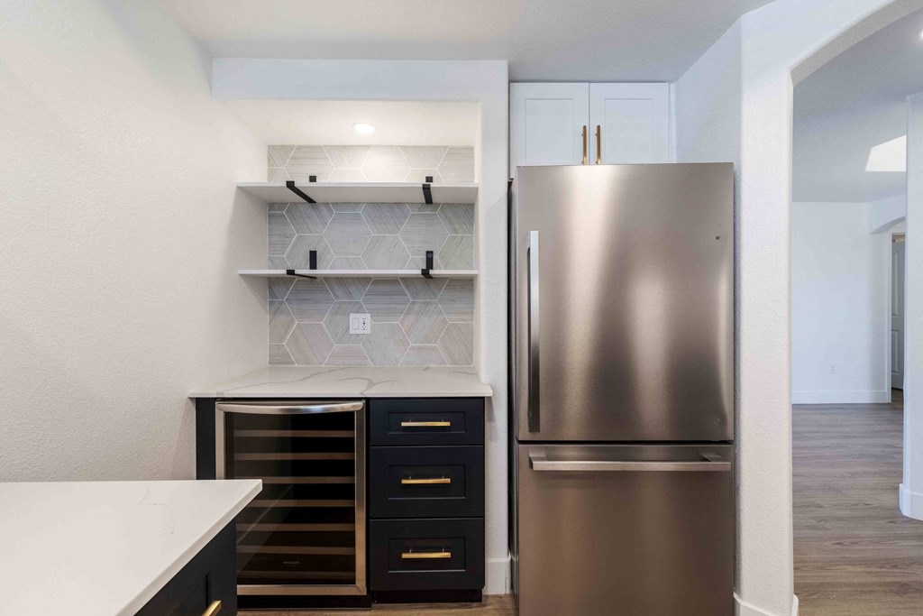 a renovated kitchen with stainless steel refrigerator and white counter tops