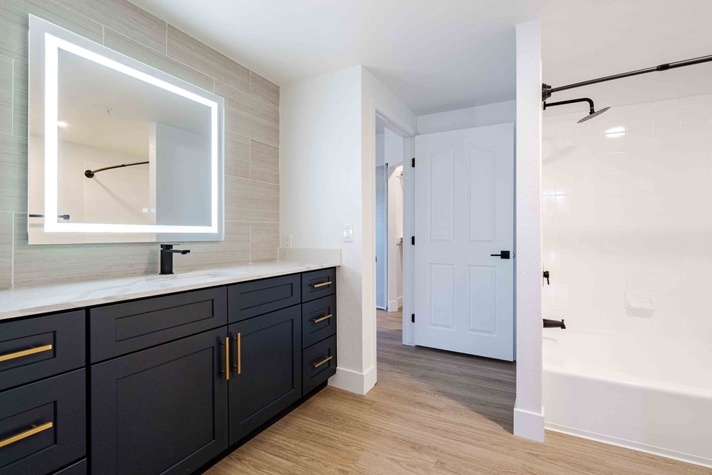 a master bathroom with black cabinets and a large mirror