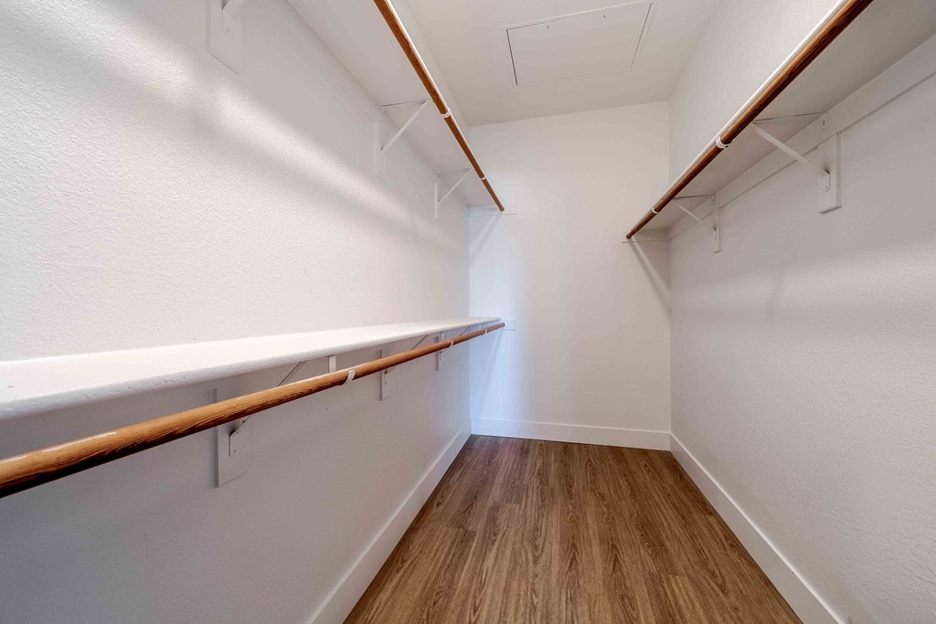a spacious walk in closet with a wood floor and white walls