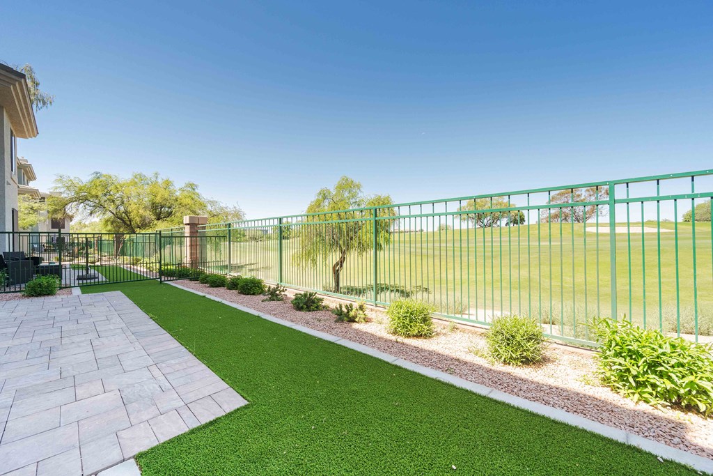 a backyard with green grass and a fence