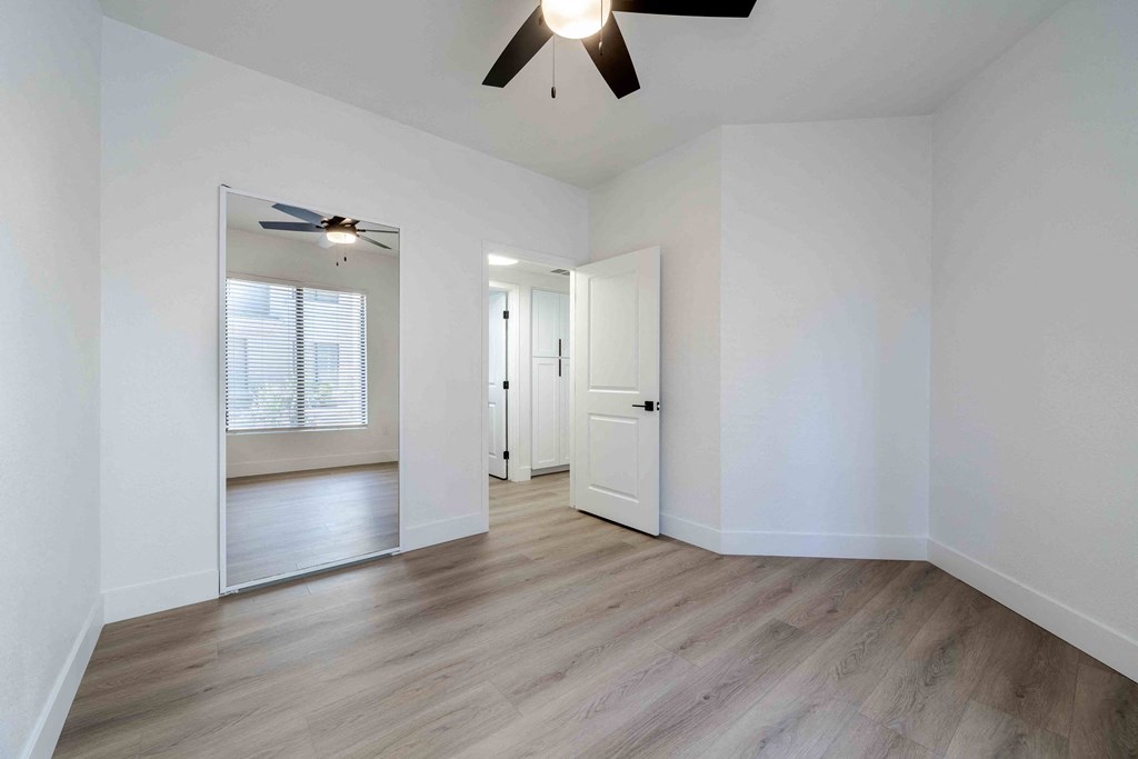 an empty living room with white walls and a ceiling fan
