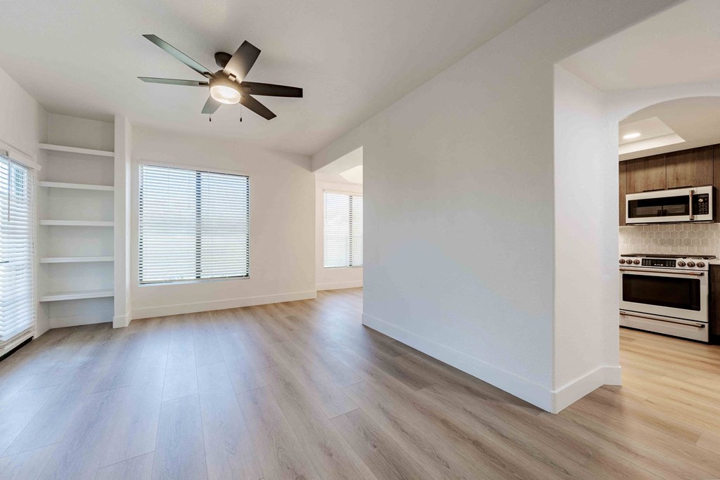 an empty living room with a ceiling fan