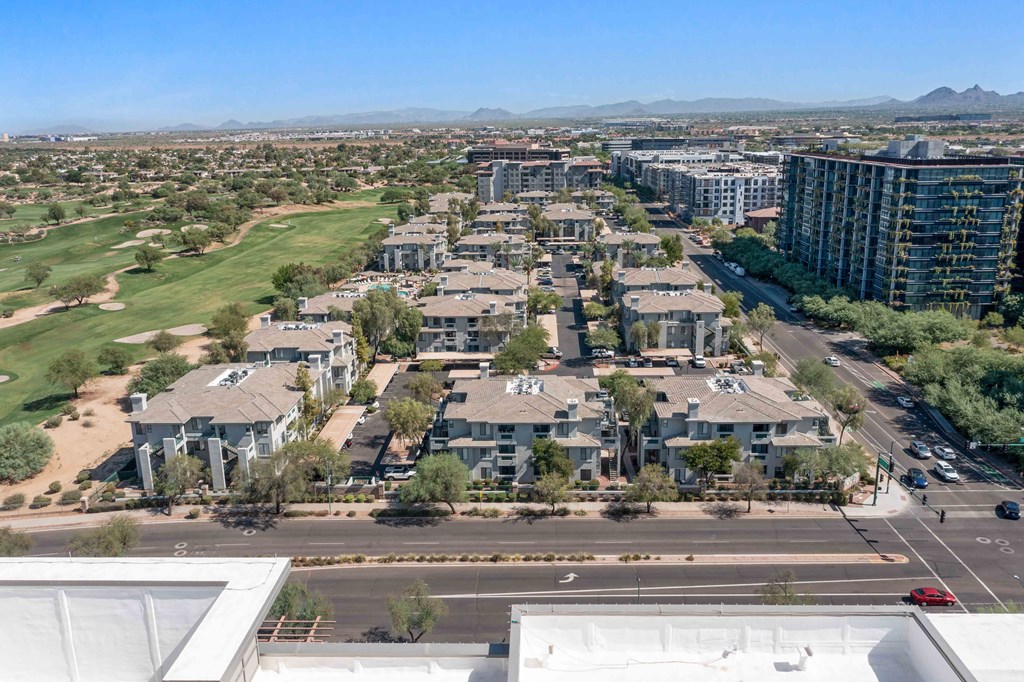 an aerial view of a large city with a golf course and mountains in the background