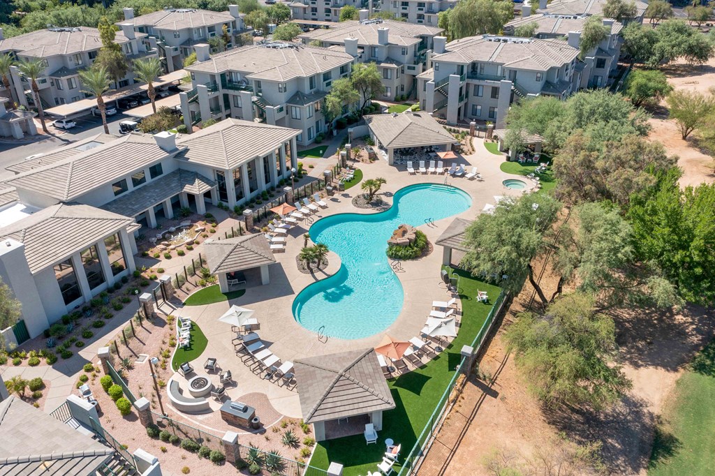 an aerial view of a resort style pool with chaise lounge chairs and umbrellas