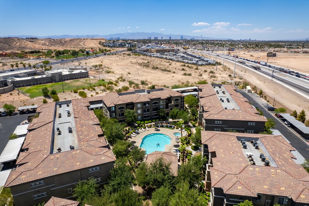an aerial view of a building with a pool in the foreground and the desert in the background