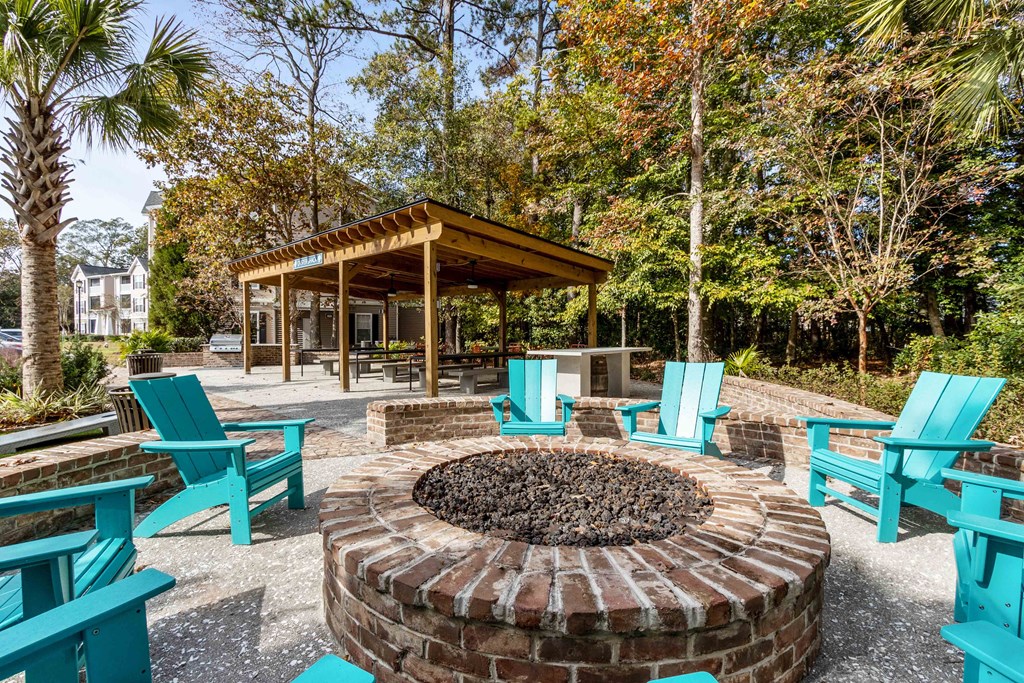 a fire pit with chairs and a gazebo in a park