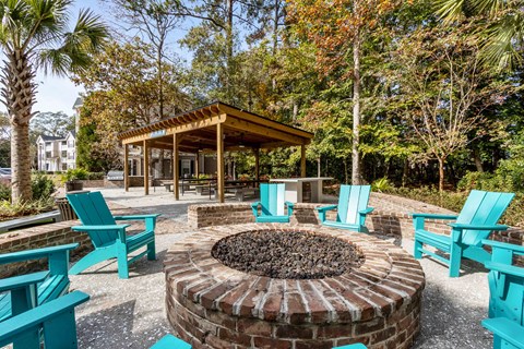 a fire pit with chairs and a gazebo in a park