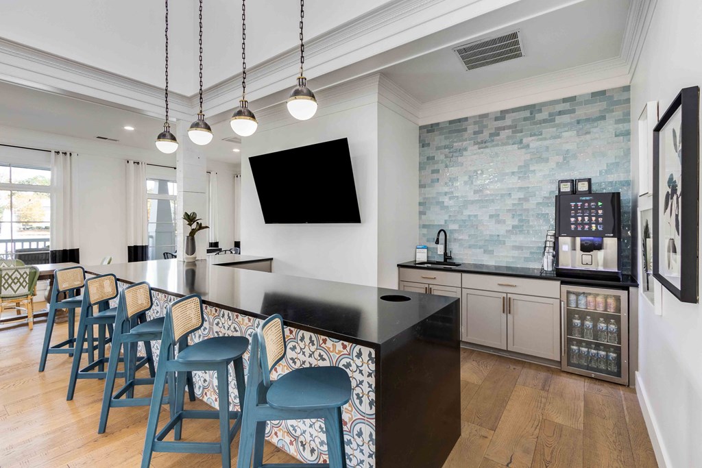 a kitchen with a long bar with blue chairs