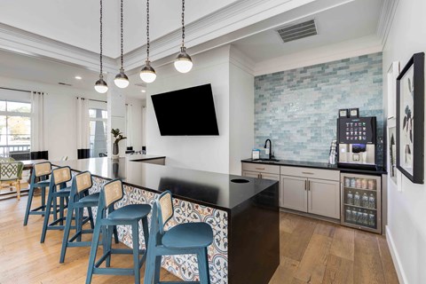 a kitchen with a long bar with blue chairs