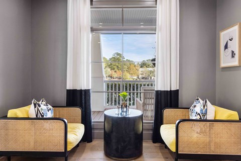 a living room with two chairs and a table and a balcony