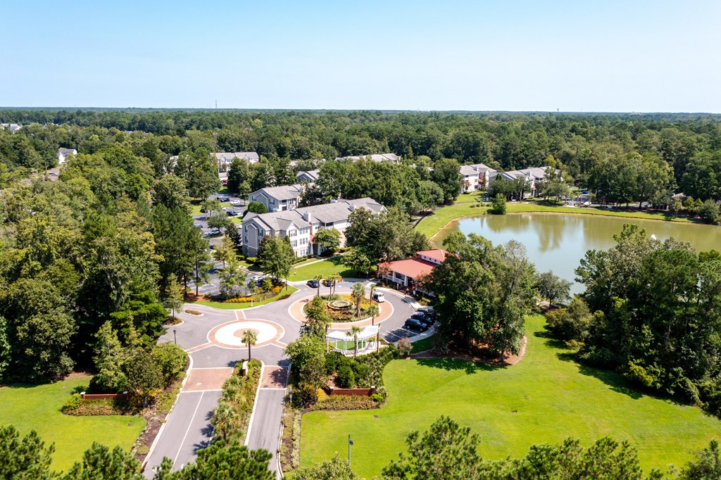 an aerial view of a park with a lake and buildings