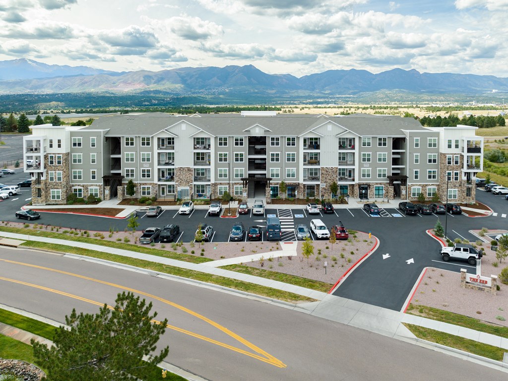 an aerial view of an apartment complex with a parking lot and mountains in the background