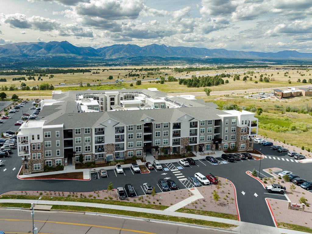 an aerial view of the zeb apartment complex with a parking lot and mountains in the background