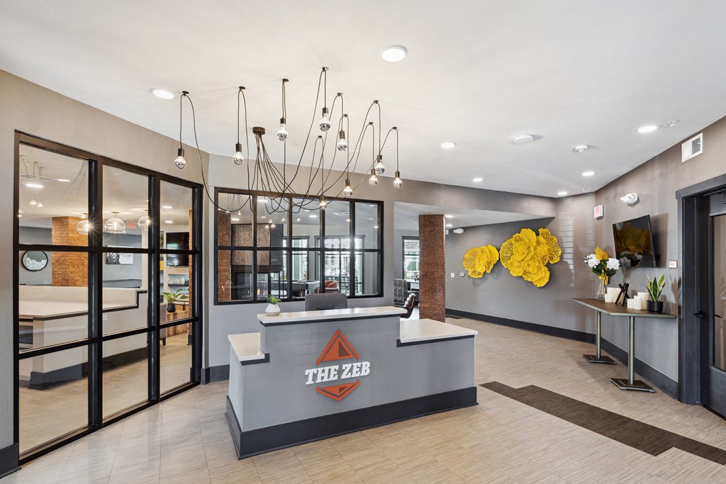 a lobby with a reception desk and a yellow chandelier at The Zeb Apartments