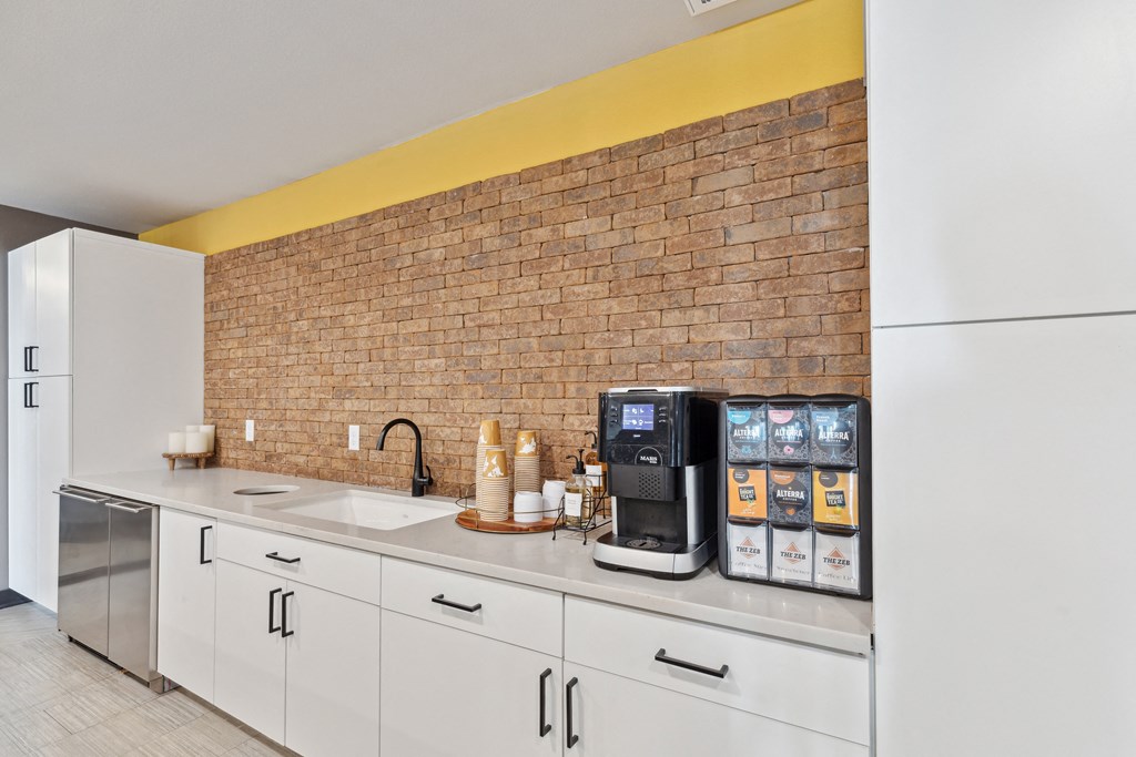 a kitchen with white cabinets and a brick wall