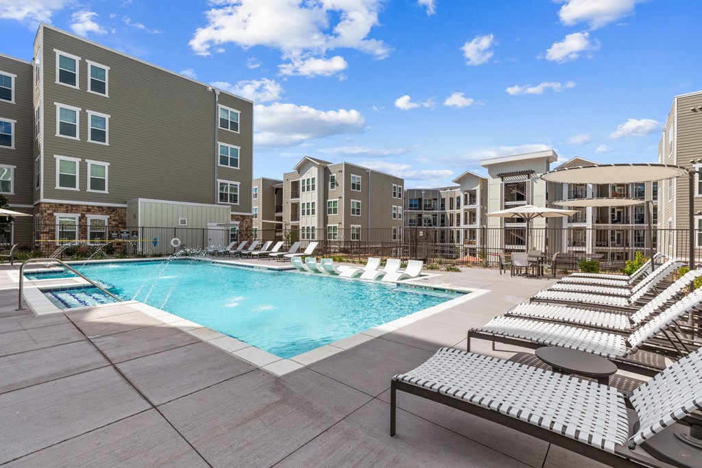 a swimming pool with lounge chairs in front of the zeb apartment building
