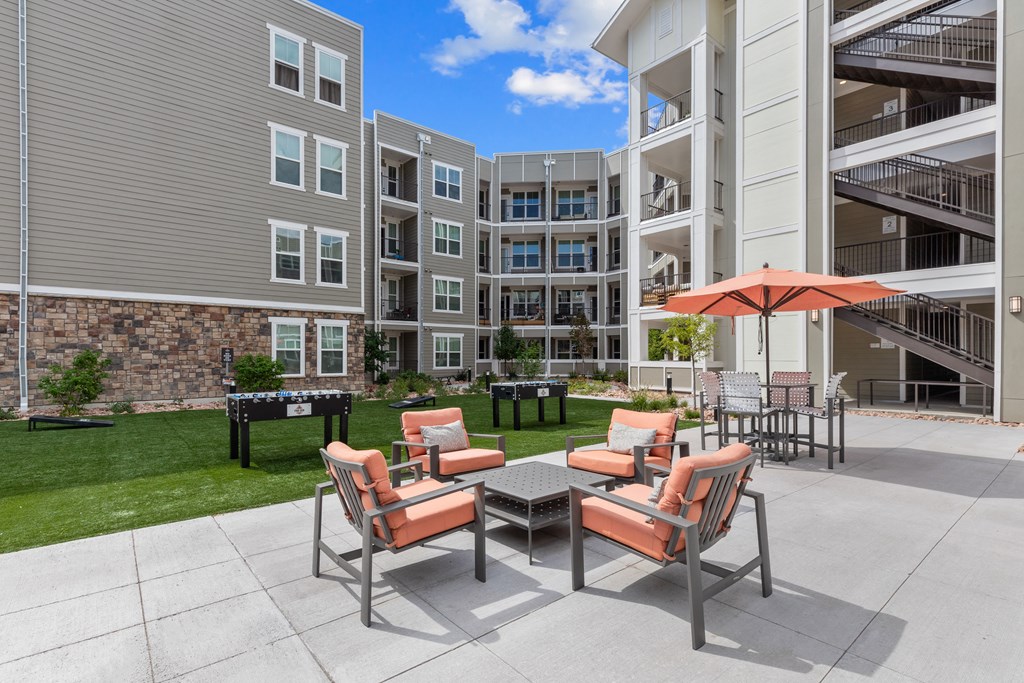 a patio with a table and chairs and an umbrella in front of an apartment building