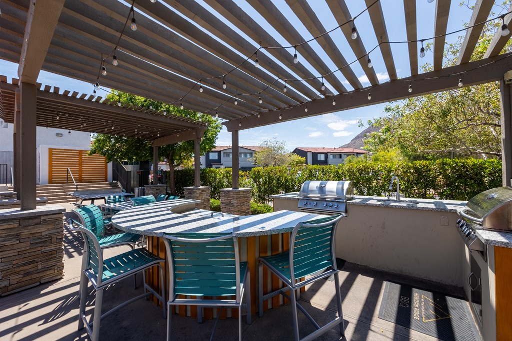an outdoor patio with a pergola and a barbecue grill