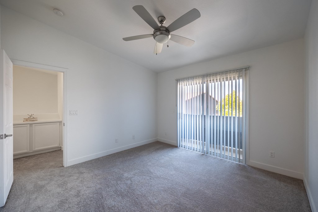 a bedroom with a ceiling fan and a large window