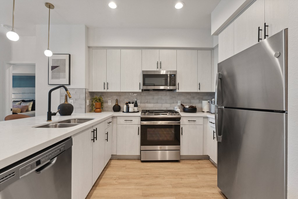 an open kitchen with stainless steel appliances and white cabinets