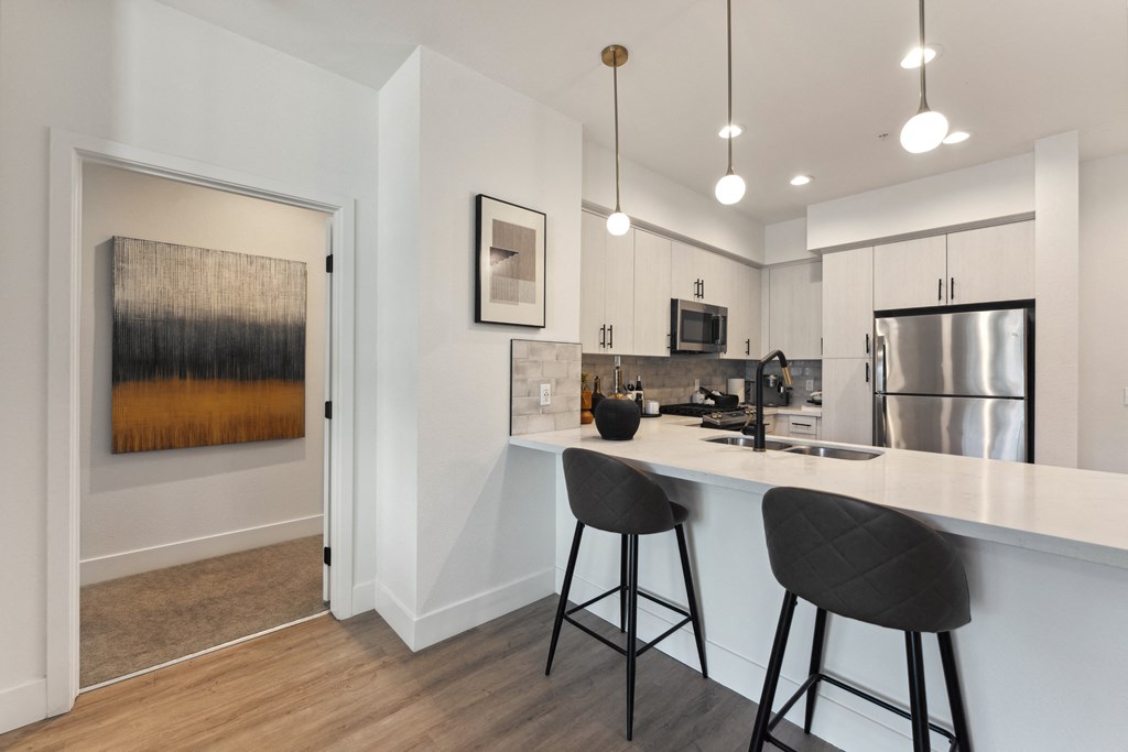 A kitchen with a white counter and bar stools.