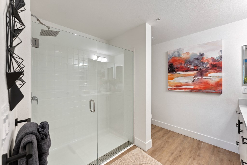 a bathroom with a glass shower and a painting on the wall