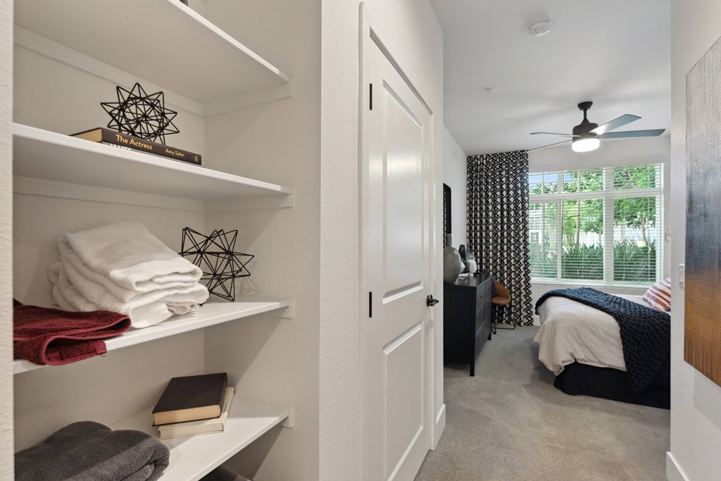 a bedroom with a closet with shelves and a bed and a window