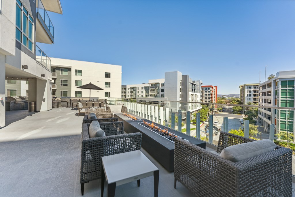 a rooftop patio with chairs and tables and buildings in the background