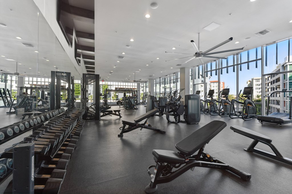 a gym with cardio machines and other exercise equipment in a building with large windows