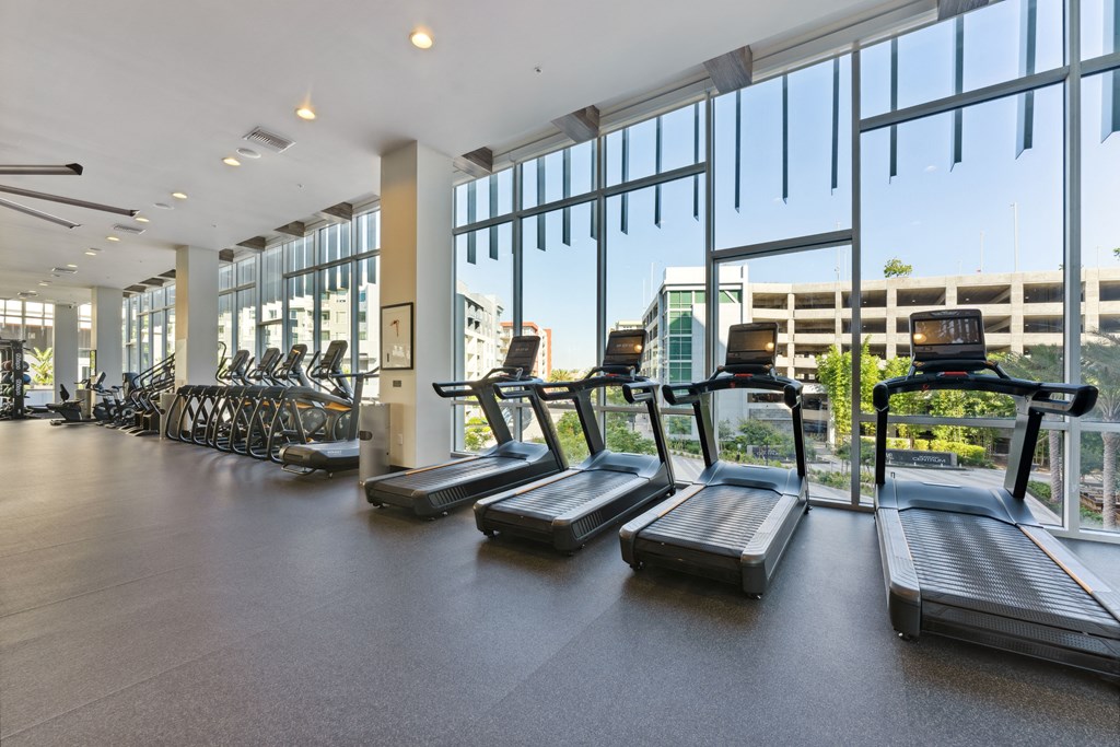 cardio equipment in the fitness center atrium of a building with floor to ceiling windows