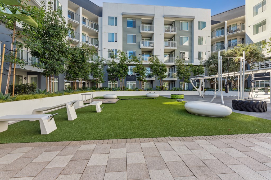 A modern apartment complex with a grassy courtyard and benches.
