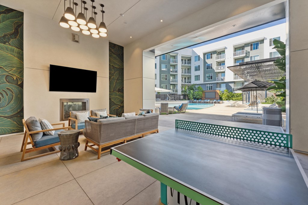 a ping pong table in a living room with a view of a pool