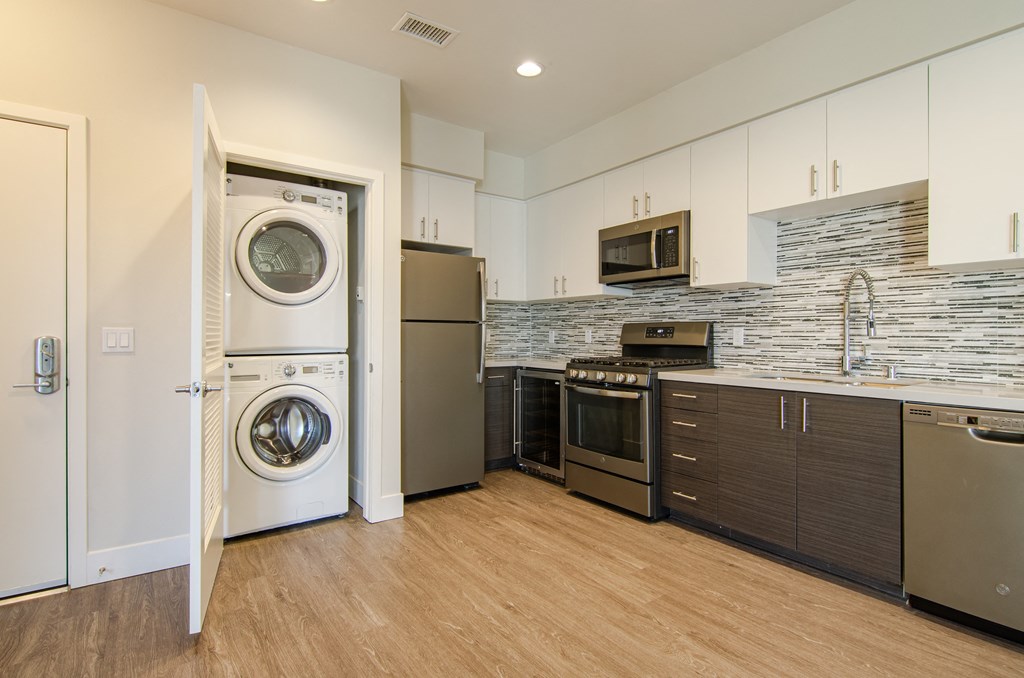 A modern kitchen with a washer and dryer built into the cabinetry.