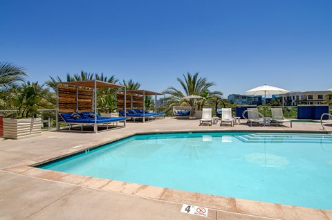 a resort style pool with lounge chairs and umbrellas