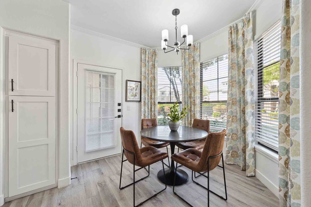a dining room with a round table with four chairs and a chandelier