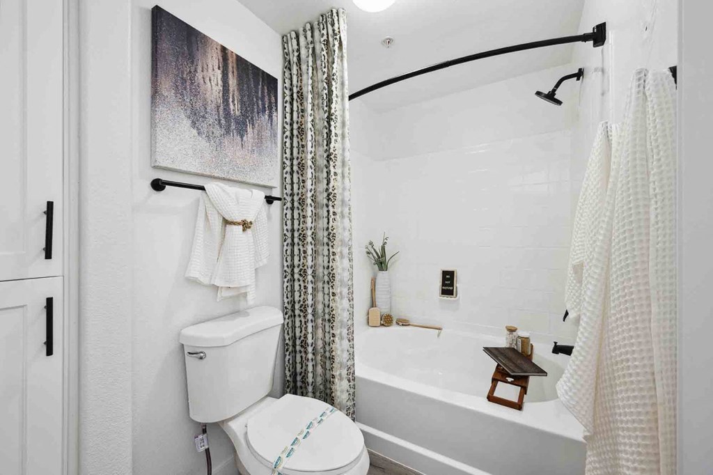 a bathroom with a white toilet next to a bathtub with a shower curtain