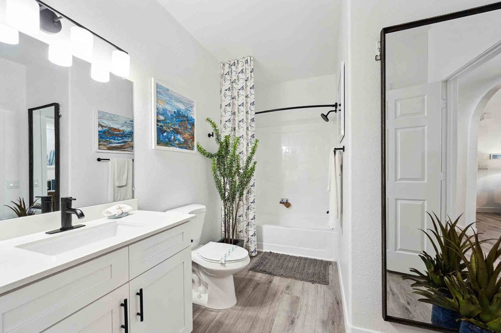 a bathroom with a white sink and toilet next to a white bathtub with a shower curtain