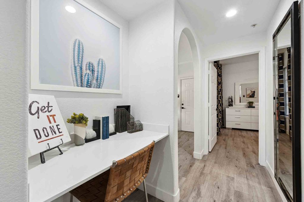 a home office with white walls and hardwood flooring