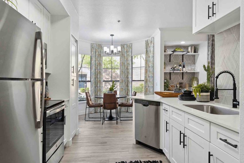Zone, Glendale, AZ, Kitchen a kitchen with white cabinets and stainless steel appliances and a dining room with a table and chairs - Photo Gallery