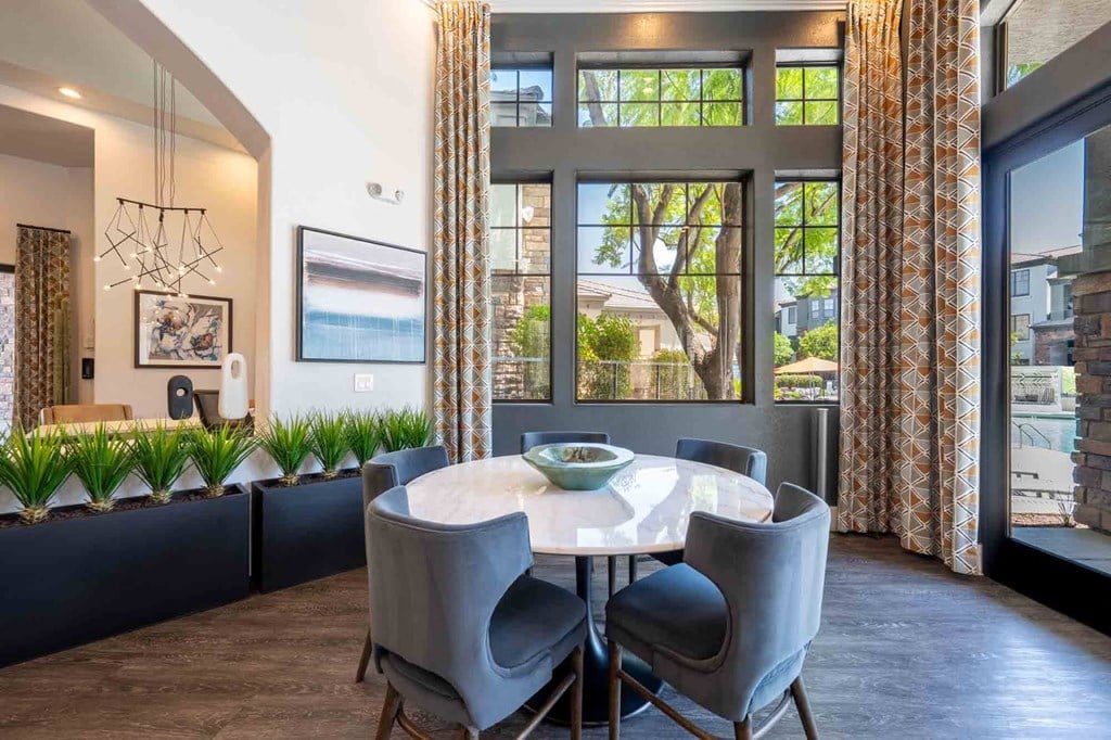 a dining area with a round table and chairs and a large window with a view of the