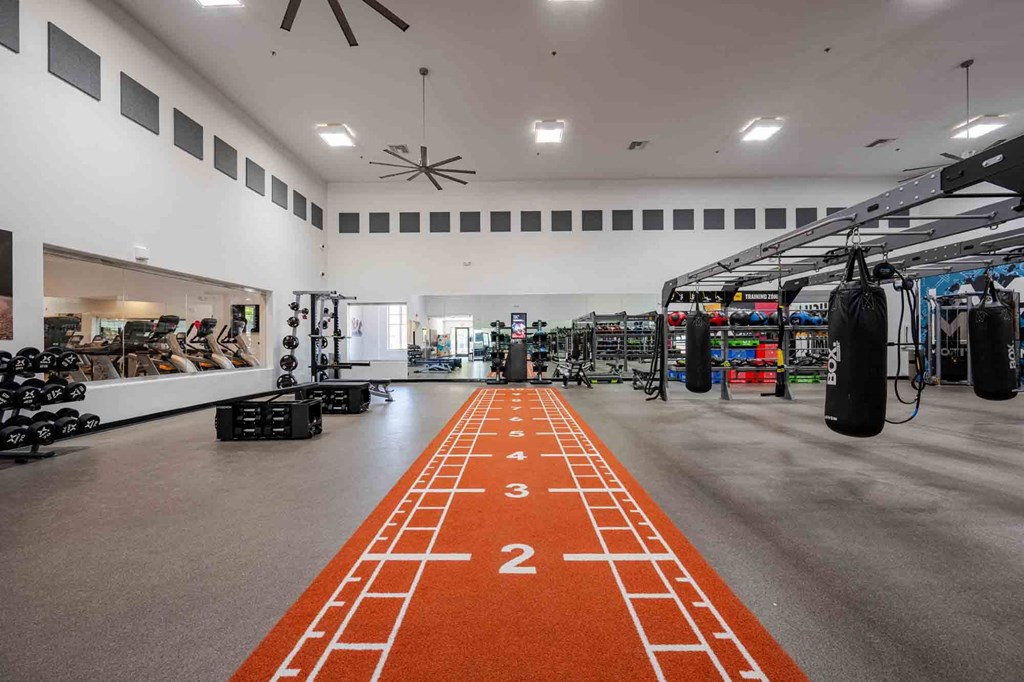 a spacious fitness center with a red track running down the middle of the room and weights on